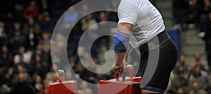 Muscular sportsman doing farmer`s walk exercise during his competition workout. Strongman sport