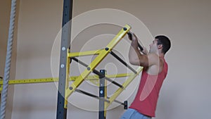 Muscular sportsman doing hard exercises on horizontal bar indoor. Strong gymnast doing pull ups during workout. Young