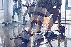 Muscular sportsman lifting barbell at gym workout