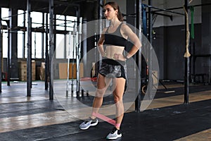 Muscular and strong girl doing exercises use fitness rubber at gym