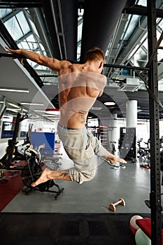 Muscular strong man exercising in the sport gym, Man doing horizontal push-ups with bars in gym. Background gym with