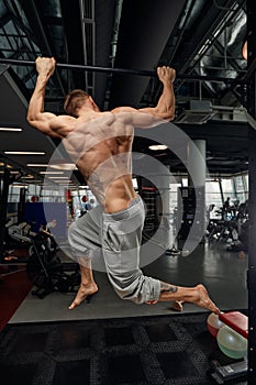 Muscular strong man exercising in the sport gym, Man doing horizontal push-ups with bars in gym. Background gym with