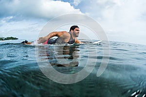 Muscular surfer paddling in the ocean