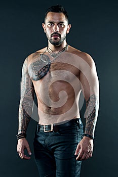 Muscular tattooed athlete look attractive. Sport and fashion concept. Handsome fit man posing wearing in jeans with