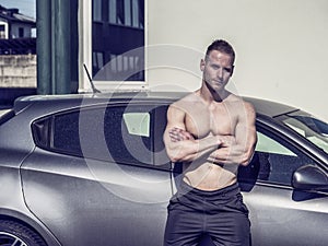 Muscular topless man outside of car
