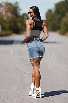 Muscular woman in denim skirt outdoors