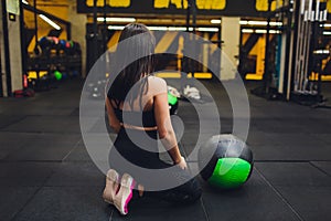 Muscular woman doing intense core workout in gym. Strong female doing core exercise on fitness mat with medicine ball in