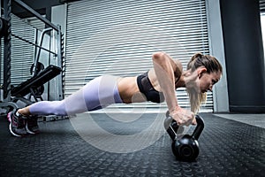 Muscular woman doing pushups with kettlebells