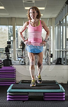 Muscular woman doing step aerobics photo