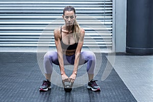 A muscular woman lifting kettlebells