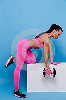 Muscular woman in pink leggings, top and gloves training with du