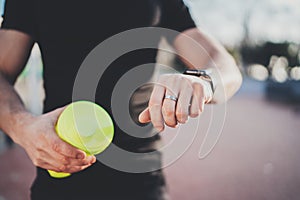 Muscular young athlete checking heart rate and calories on his smartphone application after good workout outdoor session