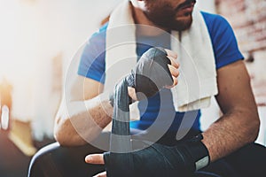 Muscular young boxer with black boxing bandages. Fists of fighter before the fight or training in sport gym. Blurred