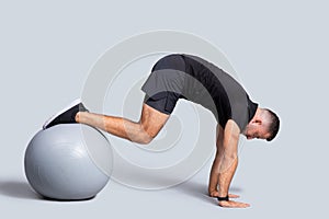Muscular young caucasian guy, make exercises for abs, hands with fit ball
