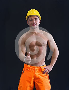 Muscular young construction worker doing thumb up sign for OK