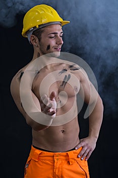 Muscular young construction worker shirtless with smoke around