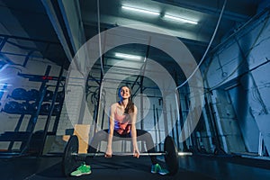 Muscular young fitness woman lifting a weight crossfit in the gym. Fitness woman deadlift barbell. Crossfit woman