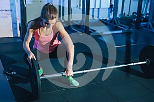 Muscular young fitness woman lifting a weight crossfit in the gym. Fitness woman deadlift barbell. Crossfit woman