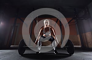 Muscular young fitness woman lifting a weight in the gym