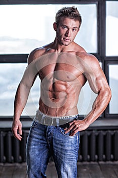 Muscular young guy posing in jeans and naked torso