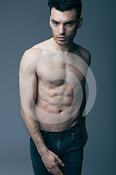 Muscular young guy posing in studio in jeans