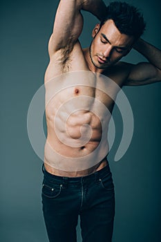Muscular young guy posing in studio in jeans