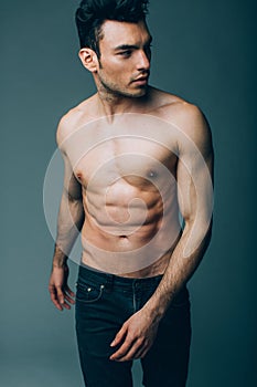 Muscular young guy posing in studio in jeans