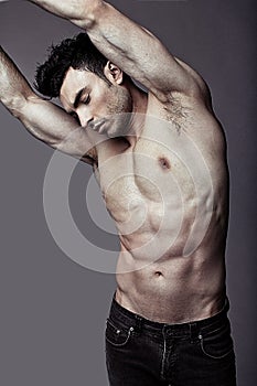 Muscular young guy posing in studio in jeans