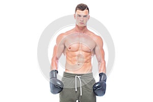 Muscular young man in black boxing gloves and shorts shows the different movements and strikes in the studio on a white