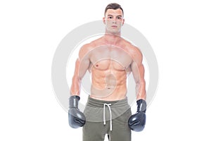 Muscular young man in black boxing gloves and shorts shows the different movements and strikes in the studio on a white