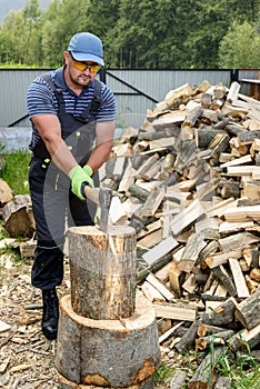 Muscular young man chopping logs