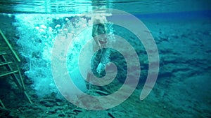 Muscular young man dives into the clear blue lake