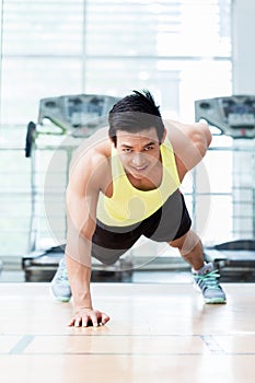 Muscular young man doing one armed pushups in gym