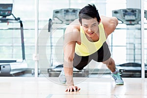 Muscular young man doing one armed pushups in gym