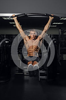 Muscular young man doing pull up on horizontal bar