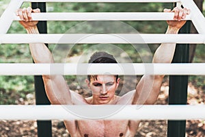 Muscular young man doing pull ups exercises