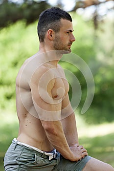 Muscular young man doing stretching exercises in the park
