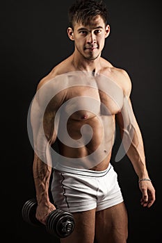 Muscular young man with a dumbbell