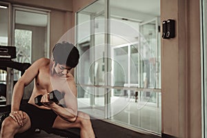 Muscular Young Man Exercising with Dumbbells in Gym - Strength Training and Fitness Concept
