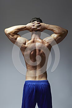 Muscular young man flexing arm muscles in sports outfit