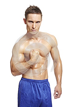 Muscular young man flexing arm muscles in sports outfit