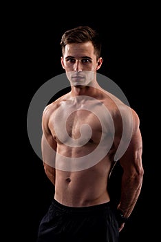 Muscular young man isolated on black background. Body-building