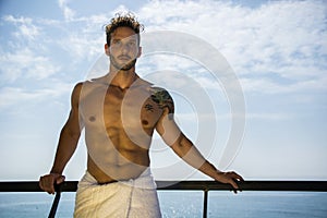 Muscular young man leaning on hand-railing on cruise ship