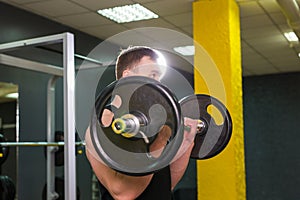 Muscular young man lifting weights in gym