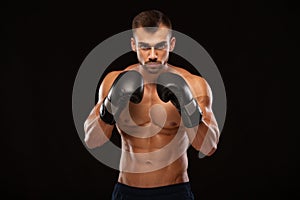 Muscular young man with perfect Torso with six pack abs, in boxing gloves is showing the different movements and strikes