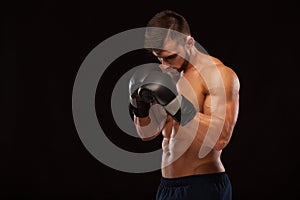 Muscular young man with perfect Torso with six pack abs, in boxing gloves is showing the different movements and strikes