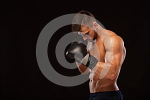 Muscular young man with perfect Torso with six pack abs, in boxing gloves is showing the different movements and strikes