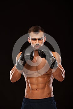 Muscular young man with perfect Torso with six pack abs, in boxing gloves is showing the different movements and strikes