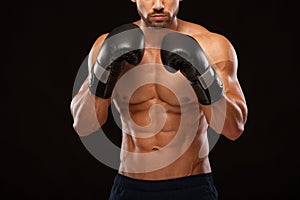 Muscular young man with perfect Torso with six pack abs, in boxing gloves is showing the different movements and strikes