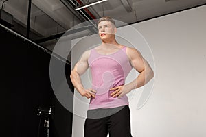 Muscular young man in pink t-shirt posing with hands on belt